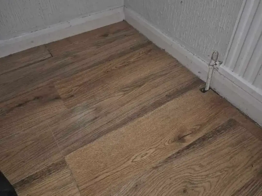 A wood-effect floor covering laid back down beside a radiator